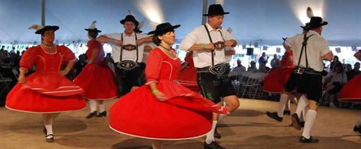 Schuhplattler dancers spinning in red dirndls and lederhosen
